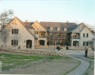 Stone estate home with a natural wood shake roof and multiple gables